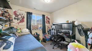 Bedroom featuring light colored carpet, a desk, and a textured ceiling