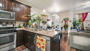 Kitchen featuring appliances with stainless steel finishes, backsplash, dark brown cabinets, and dark wood-style floors