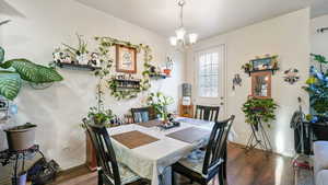 Dining area with a chandelier and dark wood-type flooring