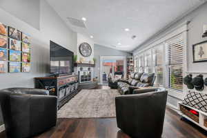 Living area with vaulted ceiling, dark wood-type flooring, recessed lighting, and a textured ceiling