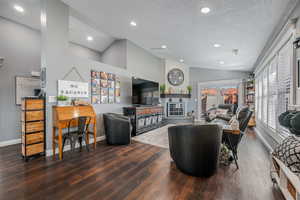 Living area featuring lofted ceiling, dark wood-type flooring, a textured ceiling, and recessed lighting