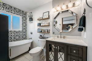 Bathroom featuring a freestanding bath, vanity, light tile patterned floors, and tile walls