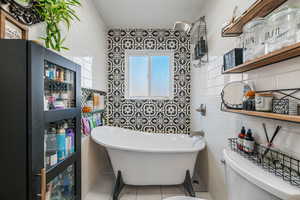 Full bathroom with a soaking tub, tile walls, and tile patterned floors