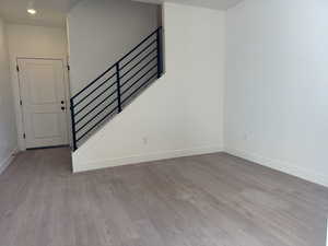 Unfurnished living room featuring light wood-style flooring and stairway