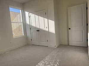 Unfurnished bedroom featuring light carpet and a closet