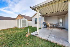 Fenced backyard featuring a storage unit, a patio area, and outdoor dining space