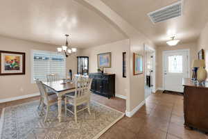 Dining area with arched walkways, healthy amount of natural light, a chandelier, and light tile patterned flooring