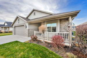 View of front of home with stone siding, concrete driveway, stucco siding, and roof with shingles