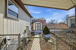 Fenced backyard featuring a gate and a storage unit