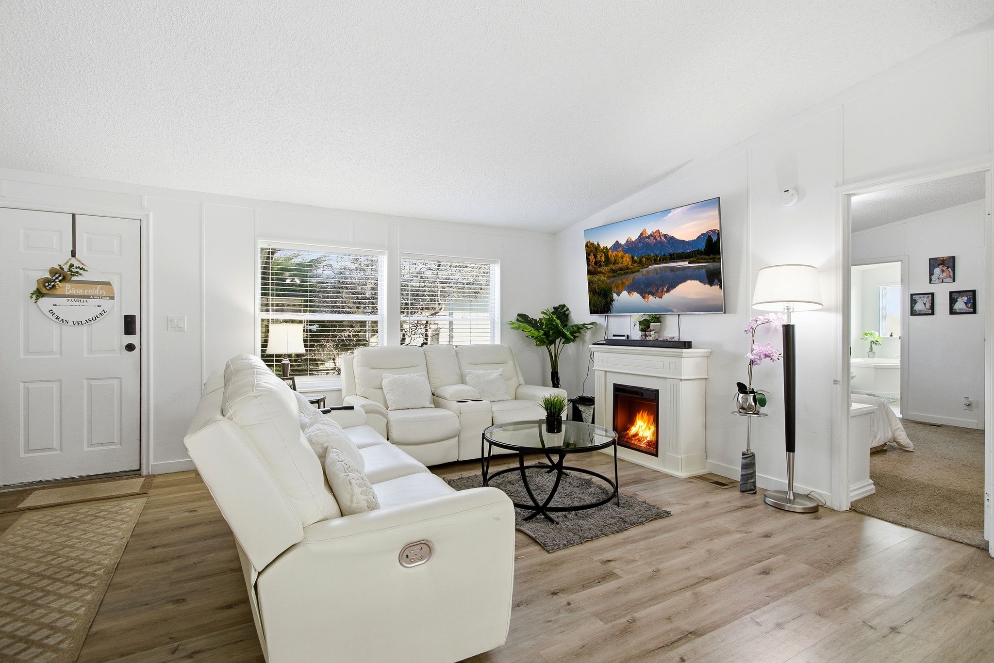 Living area featuring a warm lit fireplace, vaulted ceiling, wood finished floors, and a textured ceiling