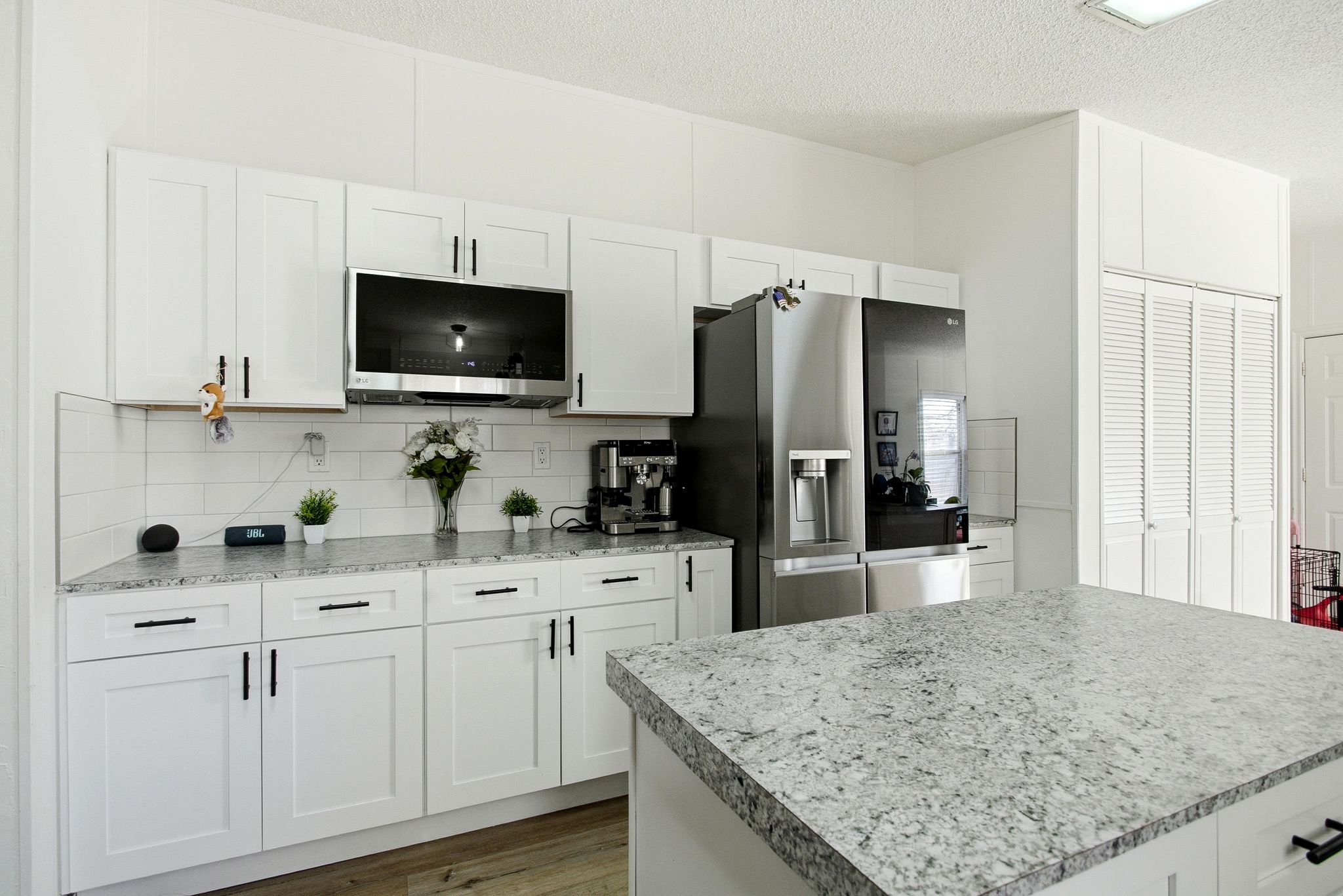 Kitchen featuring white cabinets, a textured ceiling, light countertops, appliances with stainless steel finishes, and dark wood-style floors