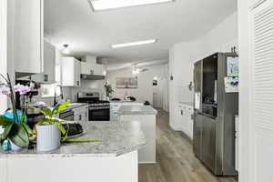 Kitchen with a kitchen island, appliances with stainless steel finishes, white cabinetry, tasteful backsplash, and a textured ceiling