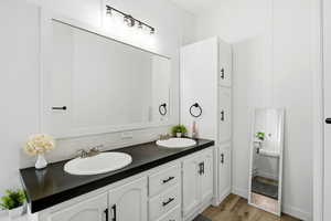 Full bath with double vanity, light wood-type flooring, and decorative backsplash