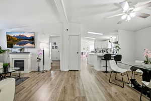 Living area featuring light wood-type flooring, a glass covered fireplace, a ceiling fan, and a textured ceiling