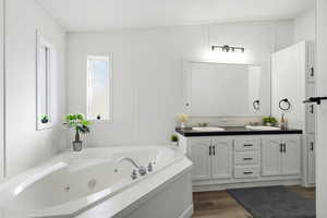 Bathroom with wood finished floors, double vanity, a whirlpool tub, a textured ceiling, and a decorative wall