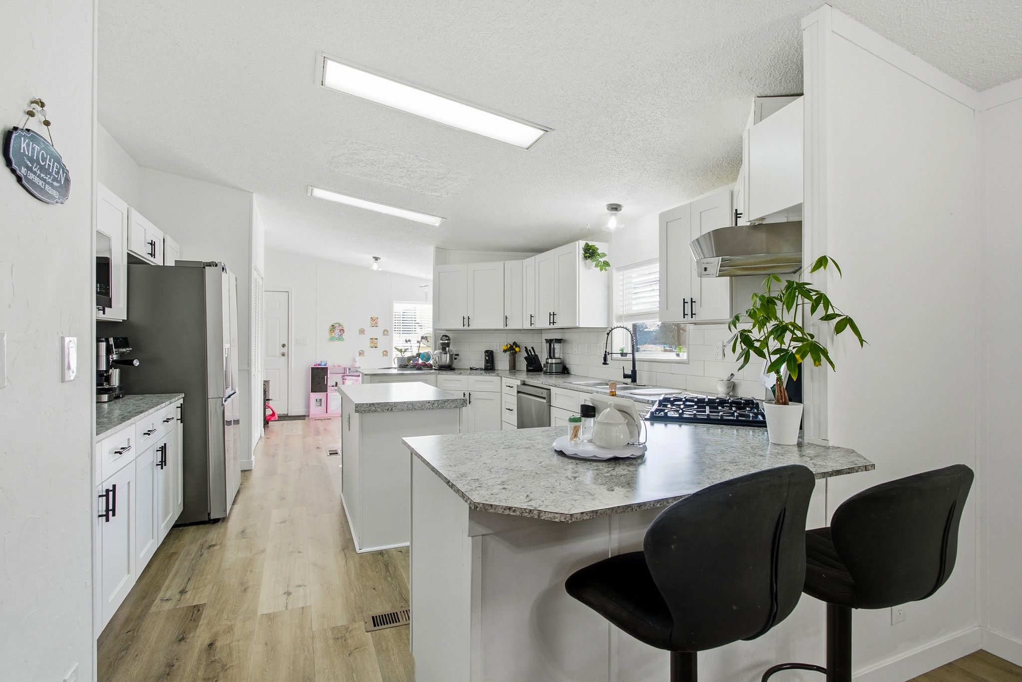 Kitchen featuring a peninsula, a kitchen breakfast bar, light wood-type flooring, appliances with stainless steel finishes, and white cabinets