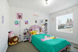 Carpeted bedroom featuring a textured ceiling and baseboards