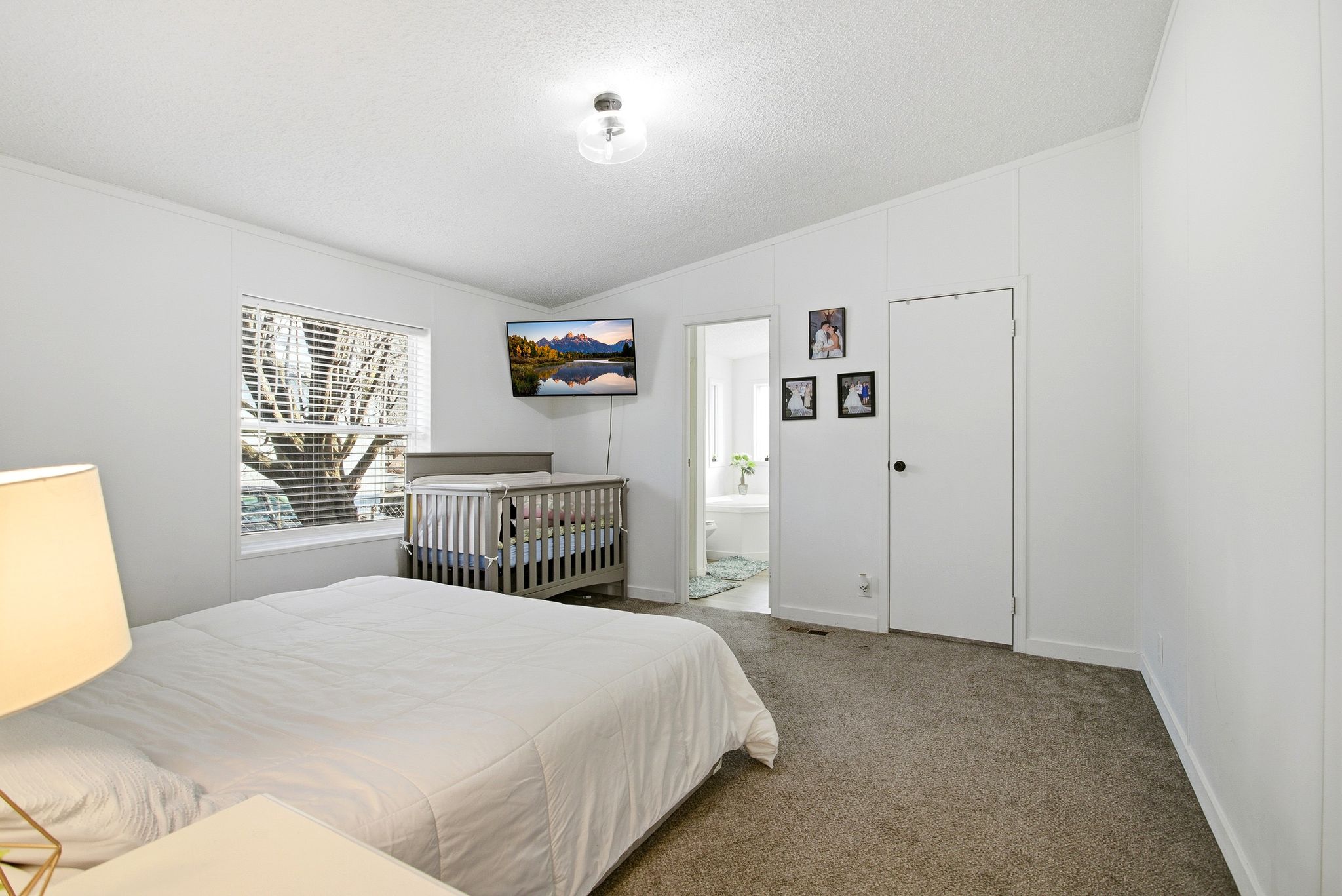 Bedroom with vaulted ceiling, carpet, a textured ceiling, crown molding, and ensuite bathroom