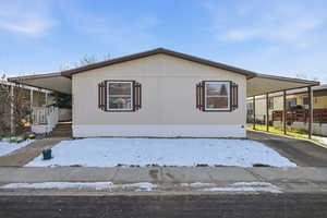 Manufactured / mobile home featuring asphalt driveway, a carport, and covered porch