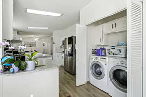 Laundry area featuring washing machine and clothes dryer, a textured ceiling, light wood-type flooring, and a ceiling fan