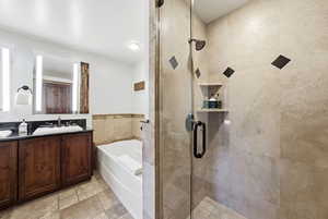 Bathroom with a garden tub, double vanity, a stall shower, and stone tile floors