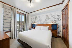 Carpeted bedroom with ornamental molding and access to outside
