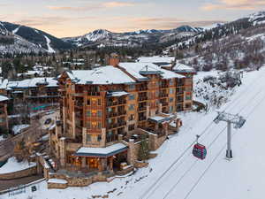 Snowy aerial view with a mountain view and a view of apartment building / complex