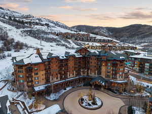 Snowy aerial view with a mountain view and a view of apartment building / complex
