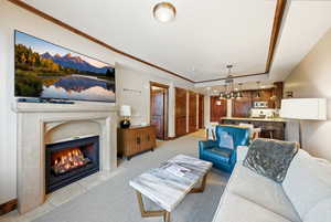 Living room with light carpet, a fireplace with flush hearth, and a raised ceiling