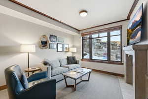 Living room with ornamental molding and a fireplace with flush hearth