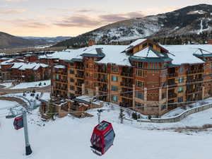 Snow covered building with a mountain view and a view of apartment building / complex