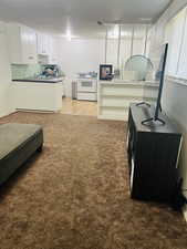 Kitchen featuring white electric range oven, light carpet, dark countertops, white cabinets, and a textured ceiling
