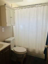 Full bathroom featuring vanity, shower / bath combination with curtain, and dark wood-type flooring