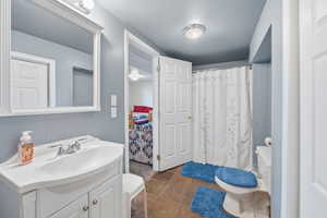 Bathroom with vanity, a shower with curtain, and stone tile flooring