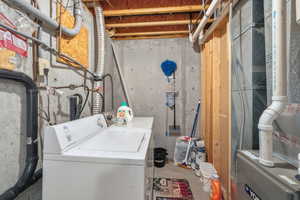 Washroom with heating unit, independent washer and dryer, and unfinished concrete flooring
