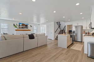 Living room featuring stairway, light wood-style flooring, and recessed lighting
