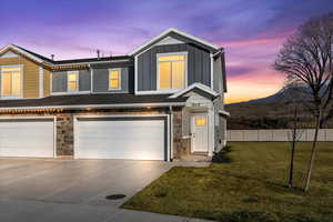 View of front of property featuring stone siding, board and batten siding, an attached garage, and concrete driveway