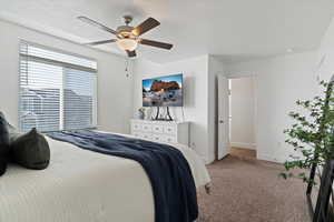 Bedroom featuring carpet flooring, a textured ceiling, and ceiling fan