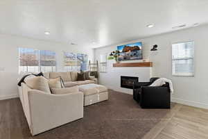Living area with a glass covered fireplace, wood tiled floors, and recessed lighting