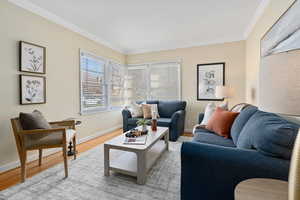 Living room with ornamental molding and wood finished floors