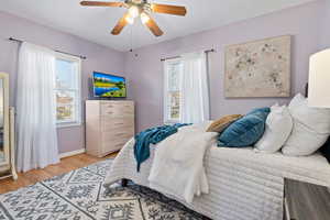 Bedroom featuring multiple windows, light wood finished floors, and a ceiling fan