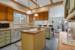 Kitchen featuring a center island, stainless steel appliances, pendant lighting, a peninsula, and green cabinetry