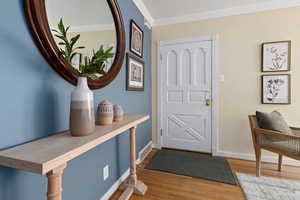 Foyer entrance with light wood-type flooring and crown molding