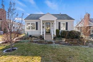 View of front of home with a front yard and a shingled roof