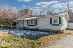 View of front of property with an attached carport, a chimney, covered porch, and a front yard