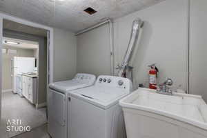 Washroom featuring a textured ceiling, washer and dryer, and light tile patterned flooring