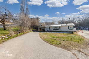 View of front of house with driveway, an attached carport, a metal roof, and covered porch