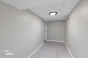 Hallway with a textured ceiling and light tile patterned floors