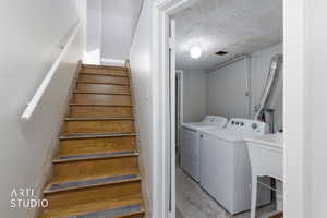Washroom featuring a textured ceiling, washer and dryer, and concrete floors