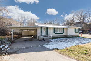 Ranch-style home featuring driveway, a chimney, and an attached carport